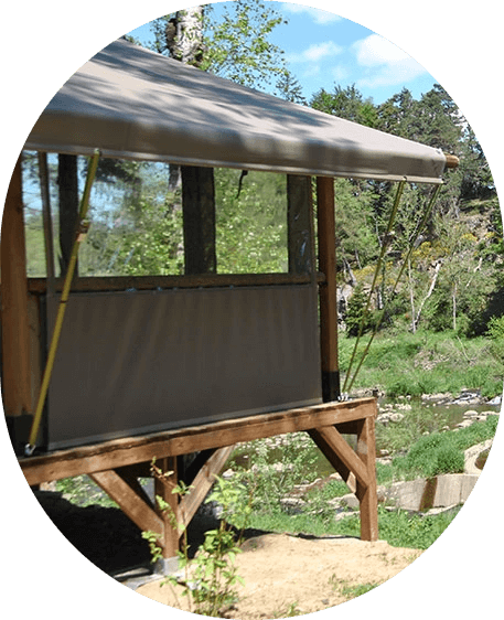 Vue extérieure de la tente Safari Trappeur avec terrasse, en location au camping les Murmures du Lignon. Une immersion totale au cœur de la Haute-Loire.