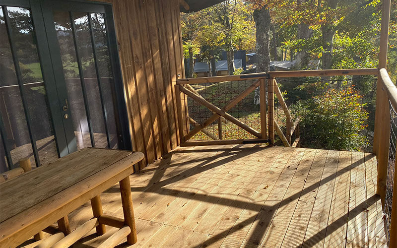 Terrasse couverte de la grande cabane, en location au camping Les Murmures du Lignon en Auvergne