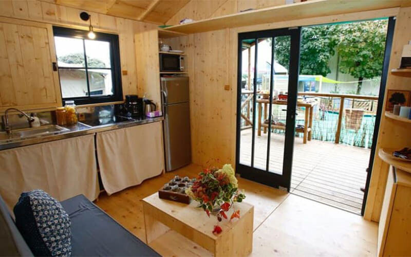 Cuisine équipée et coin salon de la grande cabane, en location au camping Les Murmures du Lignon à Tence