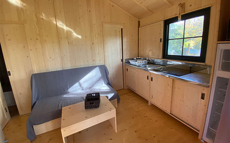 Grande cabane, en location au camping Les Murmures du Lignon en Haute-Loire : cuisine équipée et coin salon